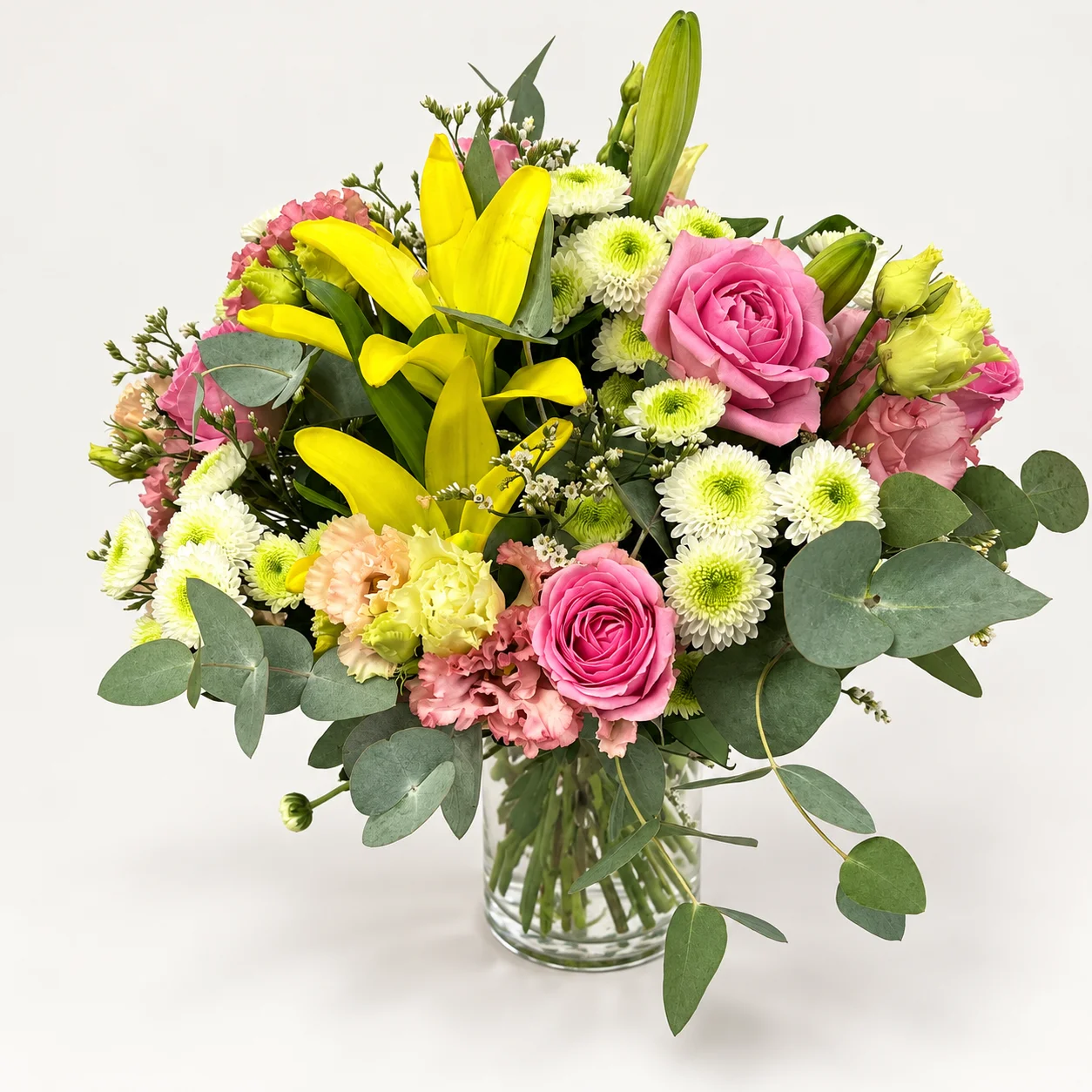 Bouquet à prix canon avec lys jaunes, roses roses et fleurs blanches dans un vase transparent