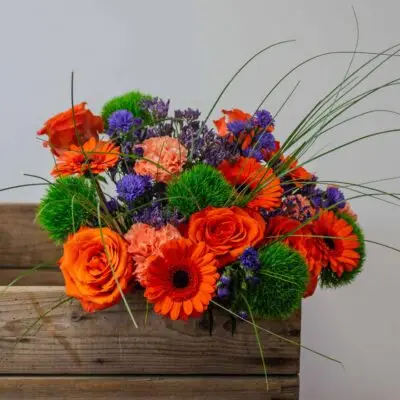 Bouquet orange, violet et vert posé sur une caisse en bois